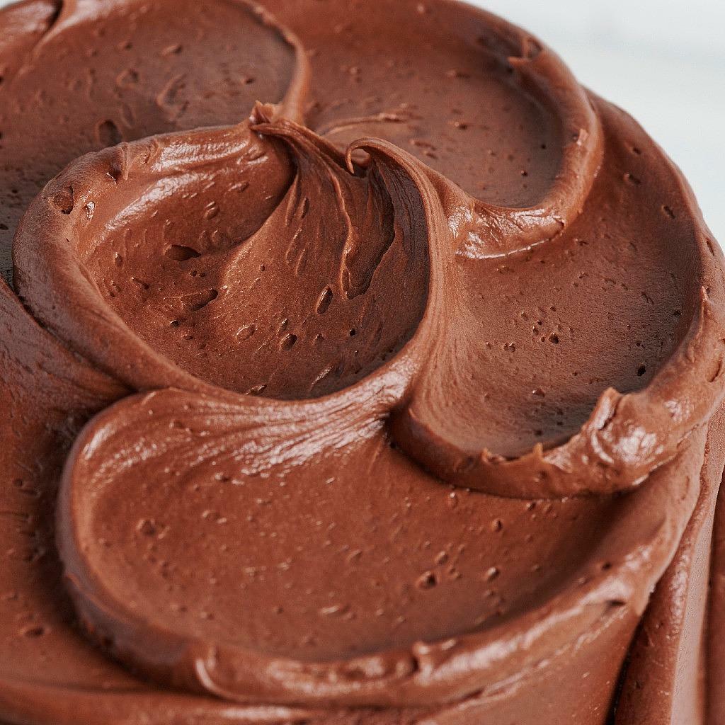 Close-up of smooth chocolate frosting swirls on a cake.