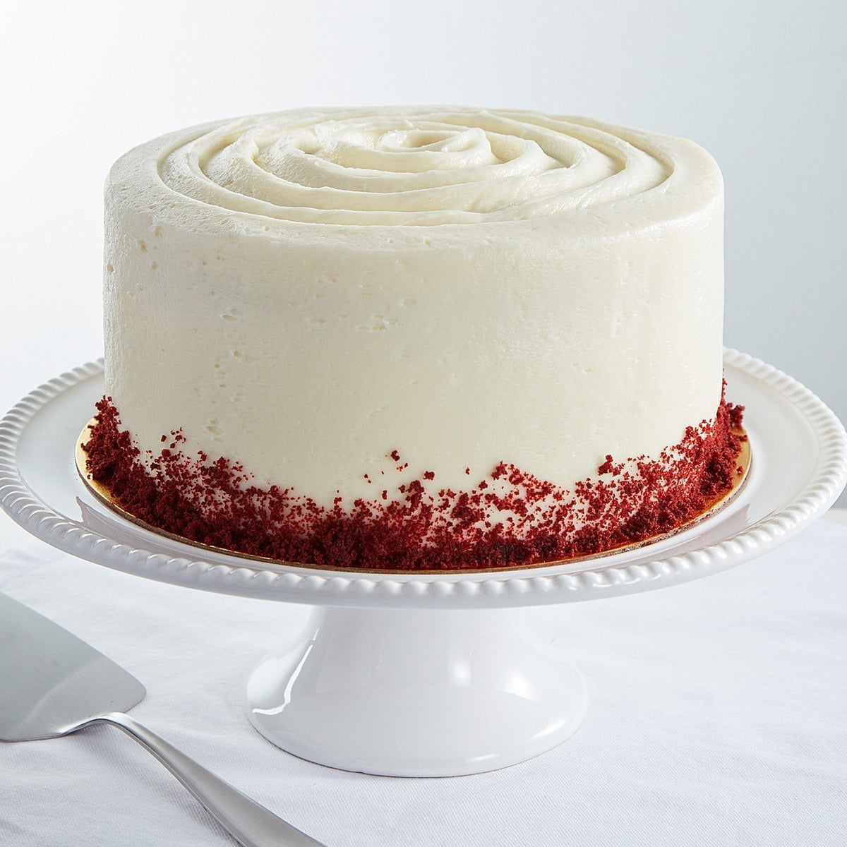 Red velvet cake with white frosting on a pedestal stand