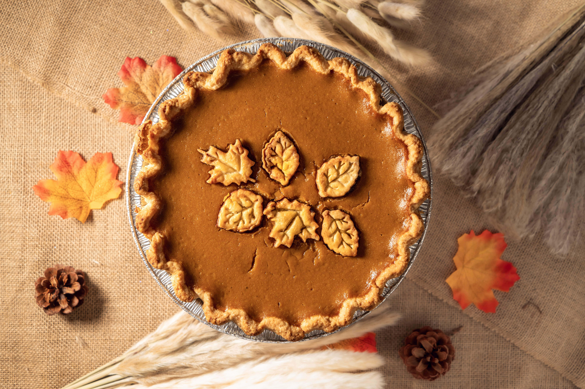 Pumpkin pie decorated with pastry leaves on burlap background