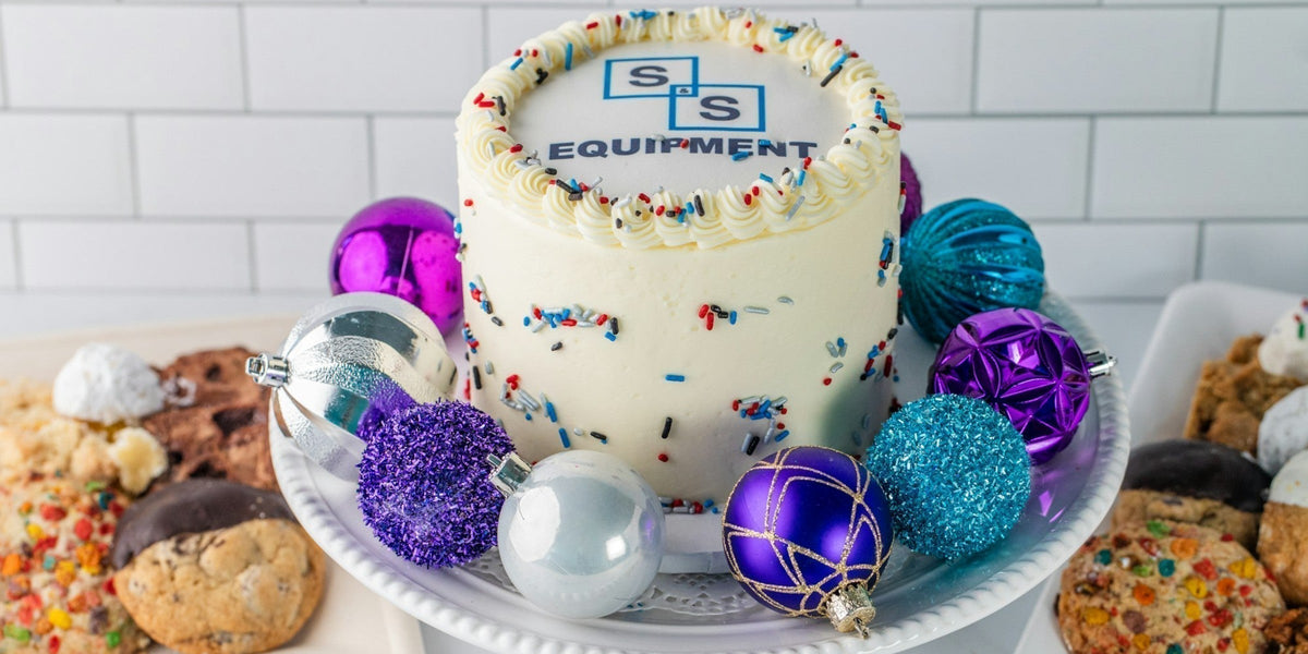 S&S Equipment branded cake surrounded by holiday ornaments